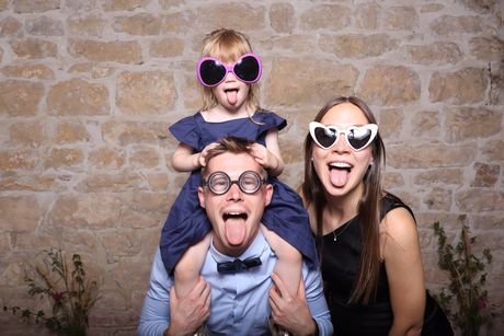 Une famille, enfant sur les épaules, tous en lunettes de soleil fantaisie.