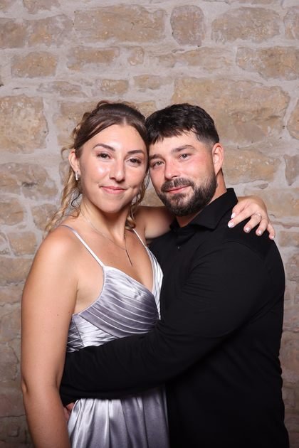Cadrage vertical : un couple enlacé devant un mur de pierre.